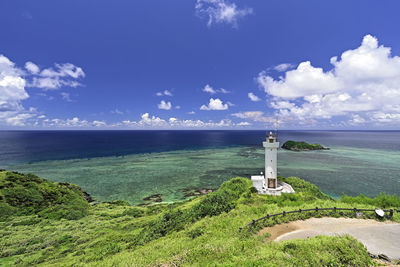 Lighthouse by sea against blue sky