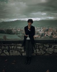 Full length of young man standing on city against sky