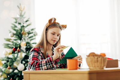 A cute teenage girl puts a letter with wishes for christmas or new year in an envelope