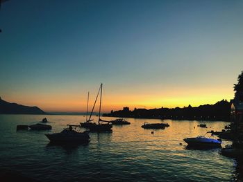 Sailboats in sea against clear sky during sunset