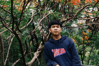 Portrait of young man standing against plants