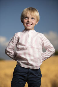 Portrait of smiling boy standing against sky