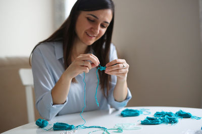 Woman embroiders with beads and makes brushes, handwork concept and housewife hobby