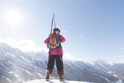 Man with backpack and ski looking at mountain standing on snow in winter