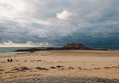 Scenic view of beach against cloudy sky