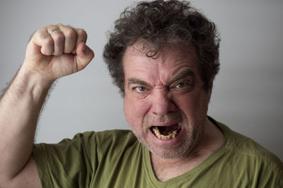 Portrait of man making face against gray background