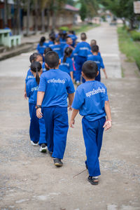 Rear view of children in uniform walking on road