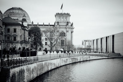 Reichtstag building by spree river against sky