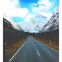 Road amidst snowcapped mountains against sky