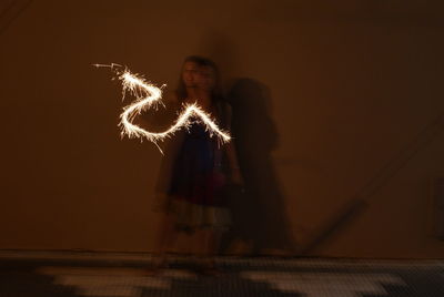 View of woman with fire crackers at night