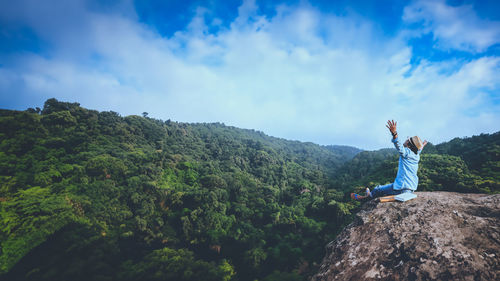 Rear view of man standing on mountain against sky