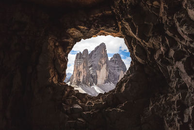 Scenic view of rock formations and mountains seen through hole against sky