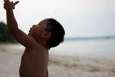 Close-up of boy at beach against sky
