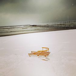 Lifeguard hut on beach against sky during winter