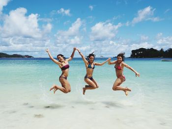 Full length portrait of young woman jumping in sea