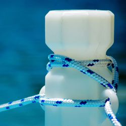 Close-up of rope tied to white bollards