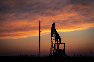 Silhouette crane against sky during sunset