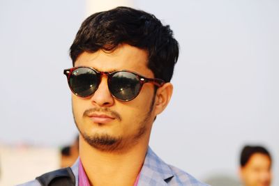 Young man wearing sunglasses against clear sky