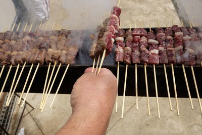 Cropped hand grilling meat over grill