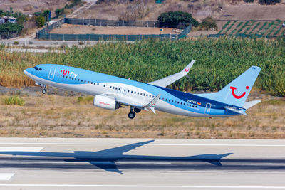 Airplane flying over airport runway against sky