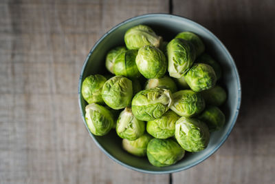 Overhead view of bowl of brussels sprouts on wooden background.