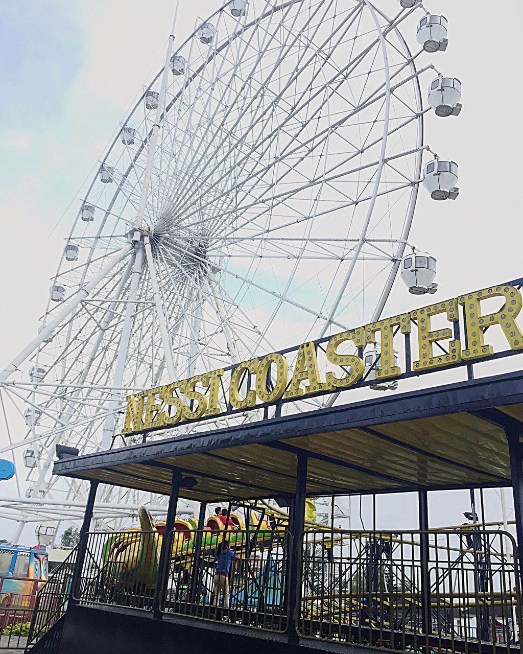 amusement park, ferris wheel, arts culture and entertainment, architecture, built structure, travel destinations, amusement park ride, day, low angle view, outdoors, sky, building exterior, no people, city