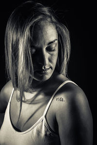 Close-up of woman with blond hair against black background