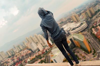 Low section of young woman in city against sky