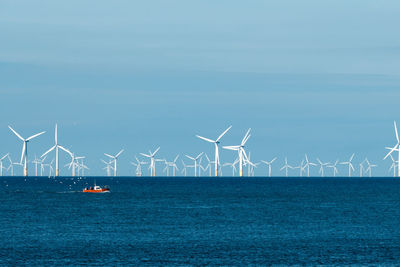 Traditional windmill by sea against sky