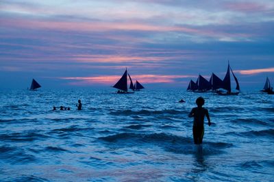 Silhouette people on beach against sky during sunset