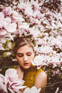 Young woman amidst pink flowers during springtime