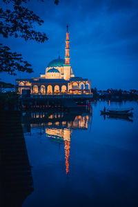 Reflection of illuminated building in water at dusk