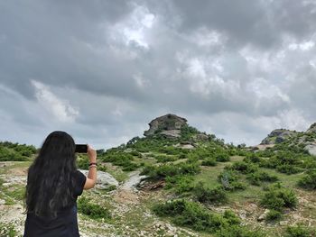 Portraits- rear view of woman standing against sky clicking photos