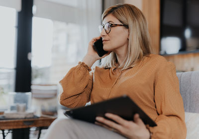 Businesswoman talking on phone while using digital tablet