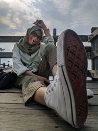 Midsection of woman sitting on seat against sky