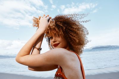 Rear view of young woman looking at sea against sky