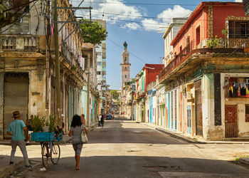 People in alley amidst buildings in city