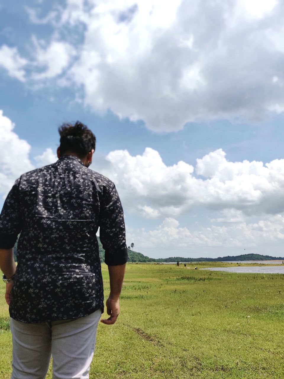 cloud - sky, sky, rear view, field, land, real people, leisure activity, nature, standing, day, lifestyles, grass, environment, landscape, non-urban scene, men, beauty in nature, tranquility, casual clothing, people, outdoors