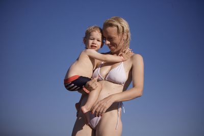 Portrait of young woman standing against clear sky