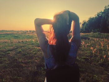 Man standing on grassy field at sunset