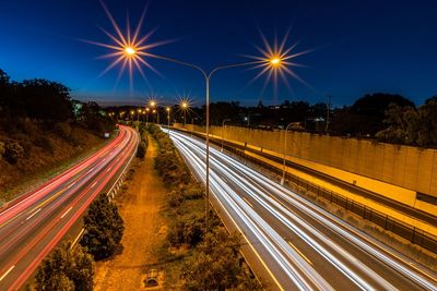 Light trails on street against sky at night