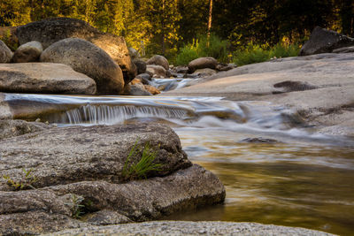 Stream flowing through rocks by river