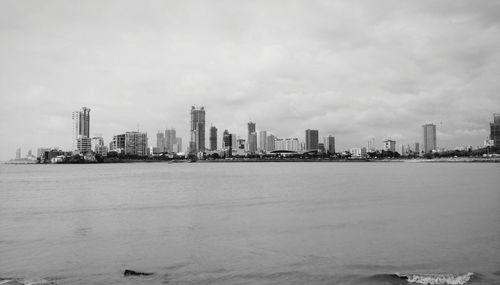 Sea by buildings against sky in city