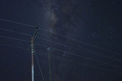 Low angle view of electricity pylon against star field at night