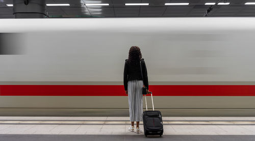 Rear view of woman standing at railroad station platform