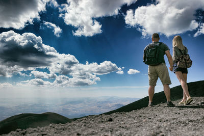 Rear view of friends standing on mountain against sky