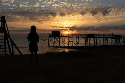 Silhouette girl  looking at sea against sky during sunset