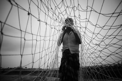 Man standing with fishing net against sky