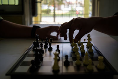 Cropped hands of people playing chess at home