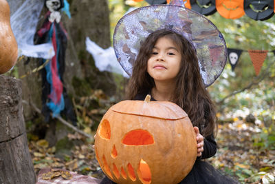 Halloween. cute arab girl in witch costume with pumpkin outdoor, having fun, celebrating halloween